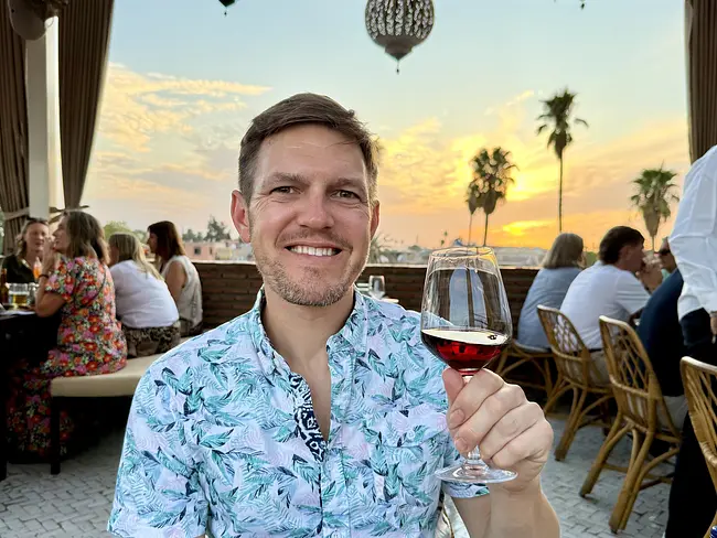 Andy enjoying wine in front of a beautiful sunset at Dardar Rooftop