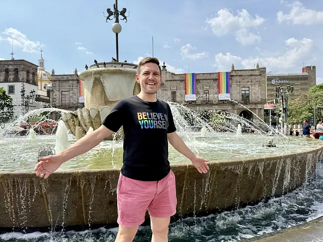 Andy in front of Guadalajara's historic center featuring rainbow flags
