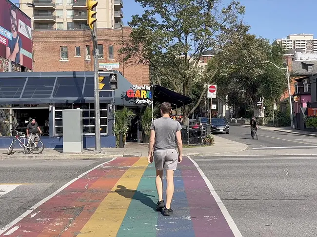 Andy crossing the rainbow crosswalk at the Church & Wellesley Gay Village