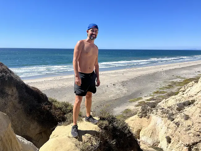 Trai shirtless atop the rocks above Black's Beach